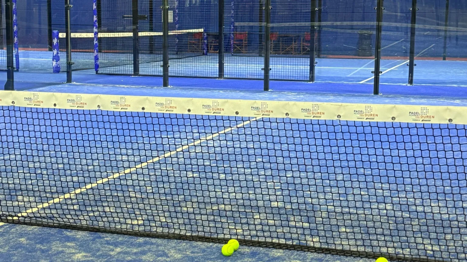 Het net van een van de indoor banen, met ballen op de baan
