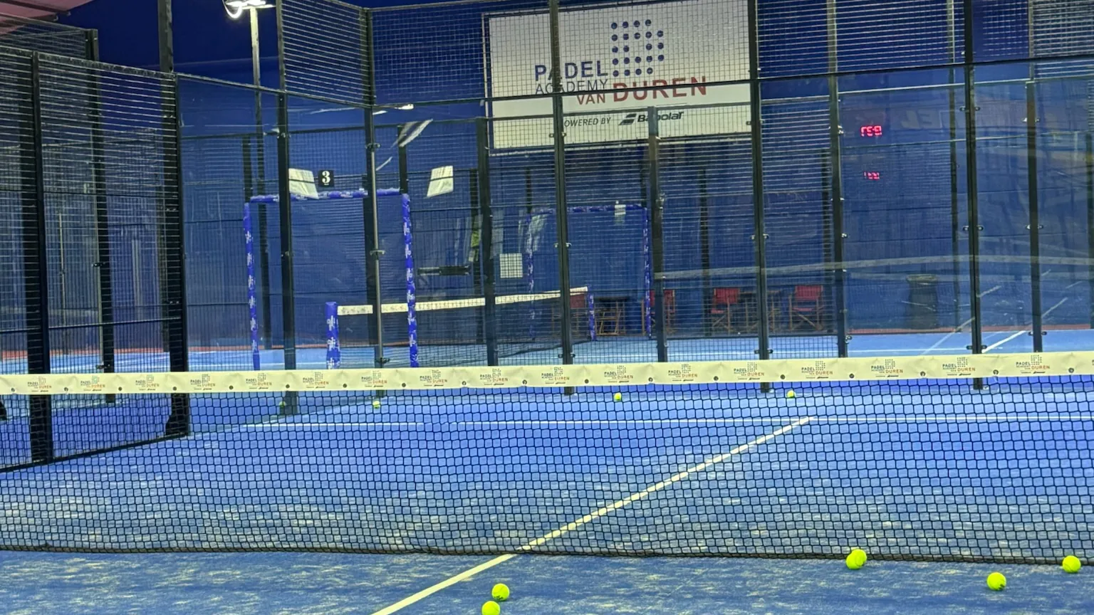 Doorkijk over een van de indoor padelbanen van Van Duren, met het bord Van Duren op de achterwand