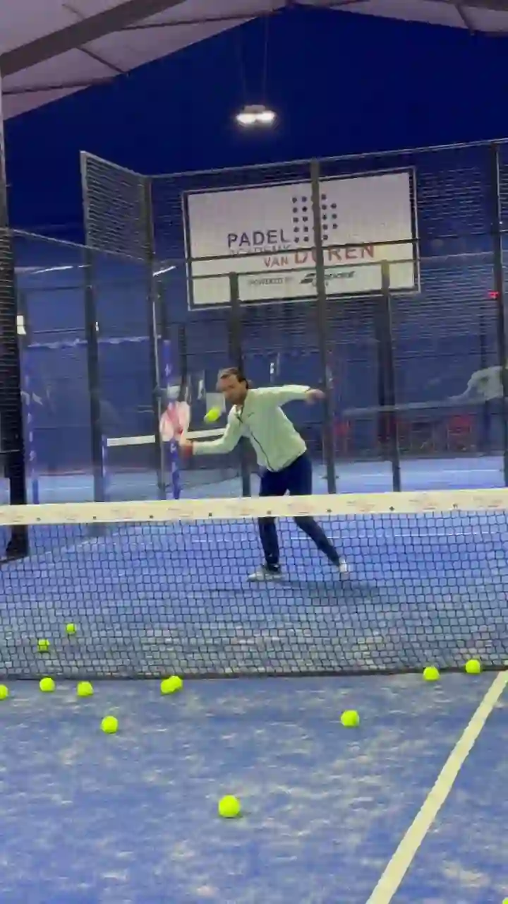 Bennet van Duren slaat ballen op een van de indoor banen, met het bord Padel Academy van Duren op de achtergrond