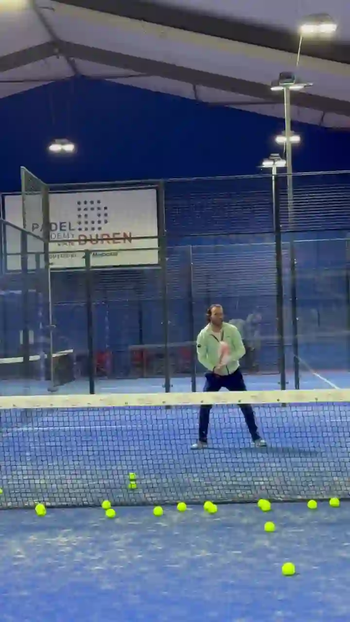 Bennet van Duren slaat ballen op een van de indoor banen, met het bord Padel Academy van Duren op de achtergrond